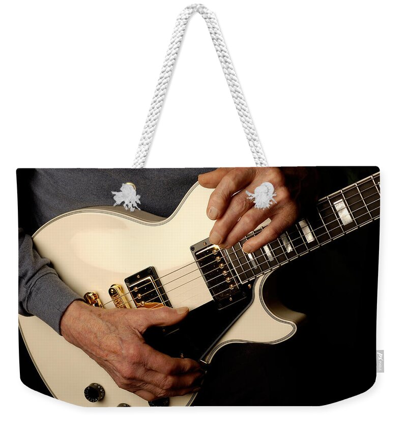 Les Paul Weekender Tote Bag featuring the photograph Les Paul's hands holding his white gibson Les Paul custom guitar by Gene Martin by David Smith