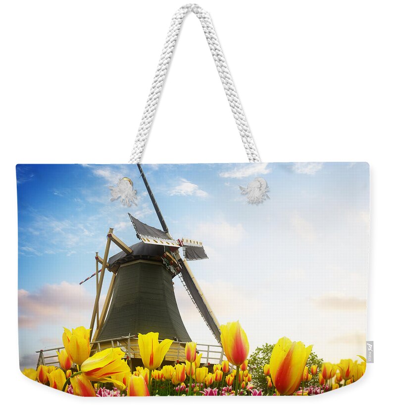 Netherlands Weekender Tote Bag featuring the photograph One Dutch Windmill Over Tulips by Anastasy Yarmolovich