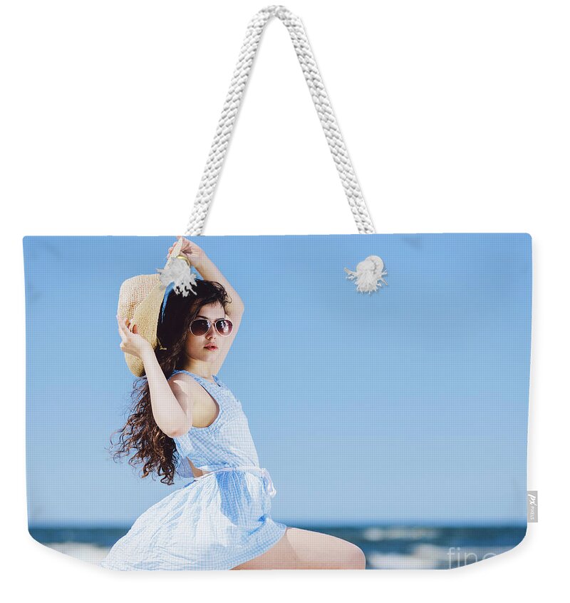 Woman Weekender Tote Bag featuring the photograph Pretty girl sitting on a sandy beach by the blue sea. by Michal Bednarek