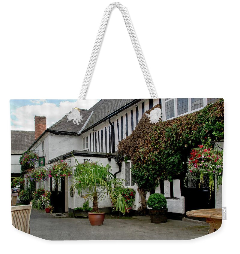White House Weekender Tote Bag featuring the photograph Quiet street with flowers on walls. by Elena Perelman