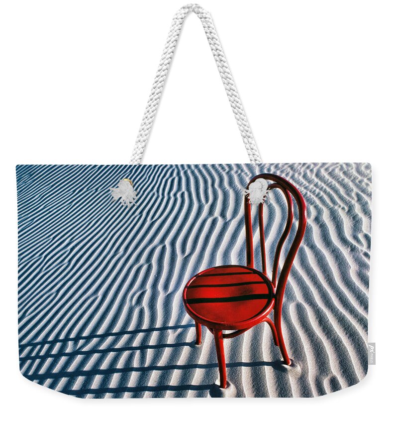 Red Weekender Tote Bag featuring the photograph Red chair in sand by Garry Gay