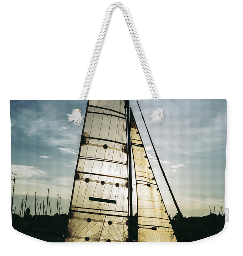 Active Weekender Tote Bag featuring the photograph Sailboat in Front of Sun in Harbor by Andreas Berthold