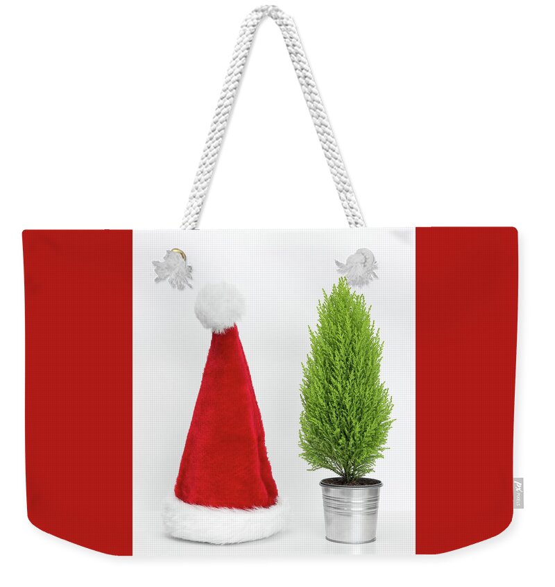 Santa Hat Weekender Tote Bag featuring the photograph Santa hat and little Christmas tree by GoodMood Art