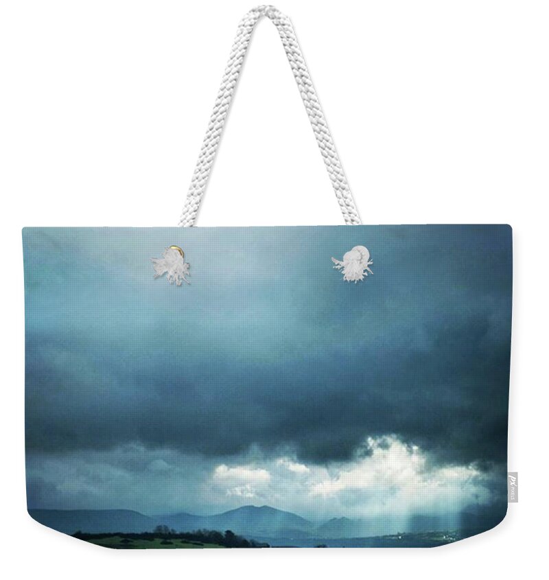 Blue Weekender Tote Bag featuring the photograph Sun Beams Through A Break In The Clouds by Aleck Cartwright