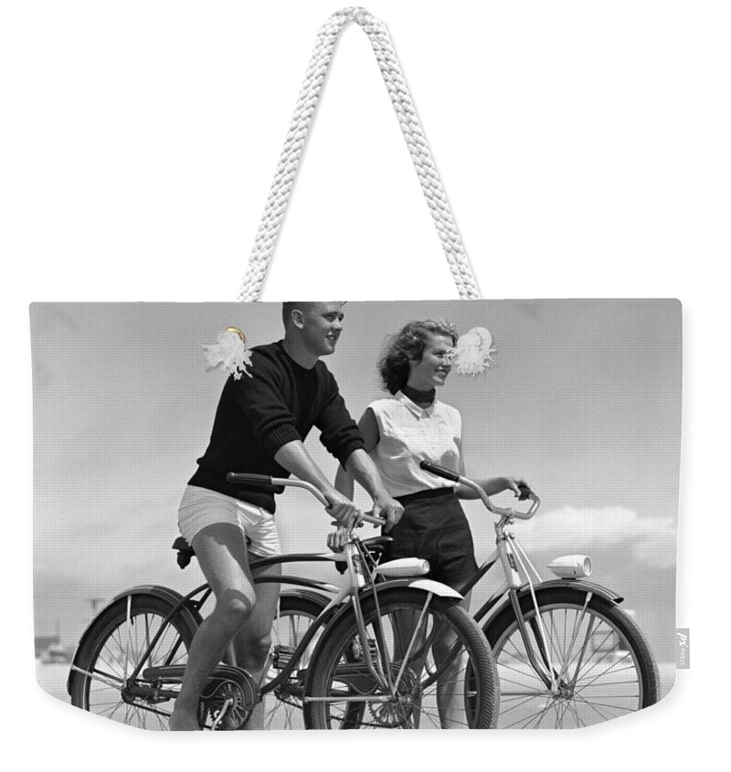 1950s Weekender Tote Bag featuring the photograph Teen Boy And Girl Biking At The Beach by H. Armstrong Roberts/ClassicStock