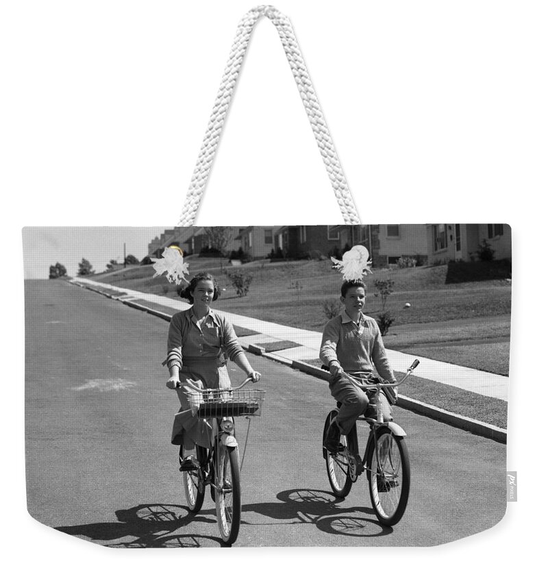 1950s Weekender Tote Bag featuring the photograph Teen Boy And Girl Riding Bikes, C.1950s by H. Armstrong Roberts/ClassicStock
