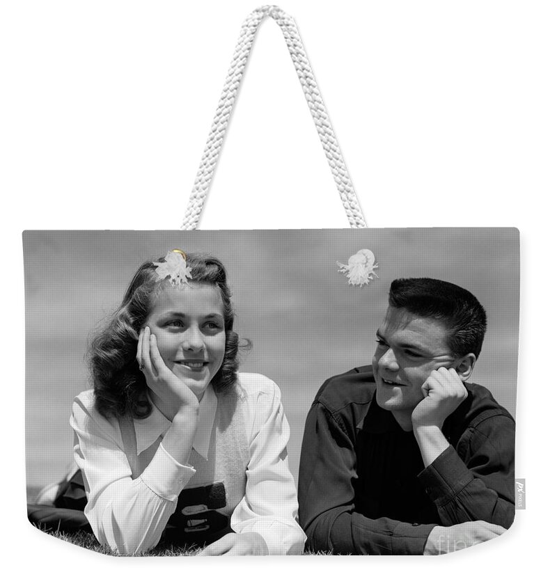 1950s Weekender Tote Bag featuring the photograph Teen Couple Lying In Grass, C.1950s by H. Armstrong Roberts/ClassicStock