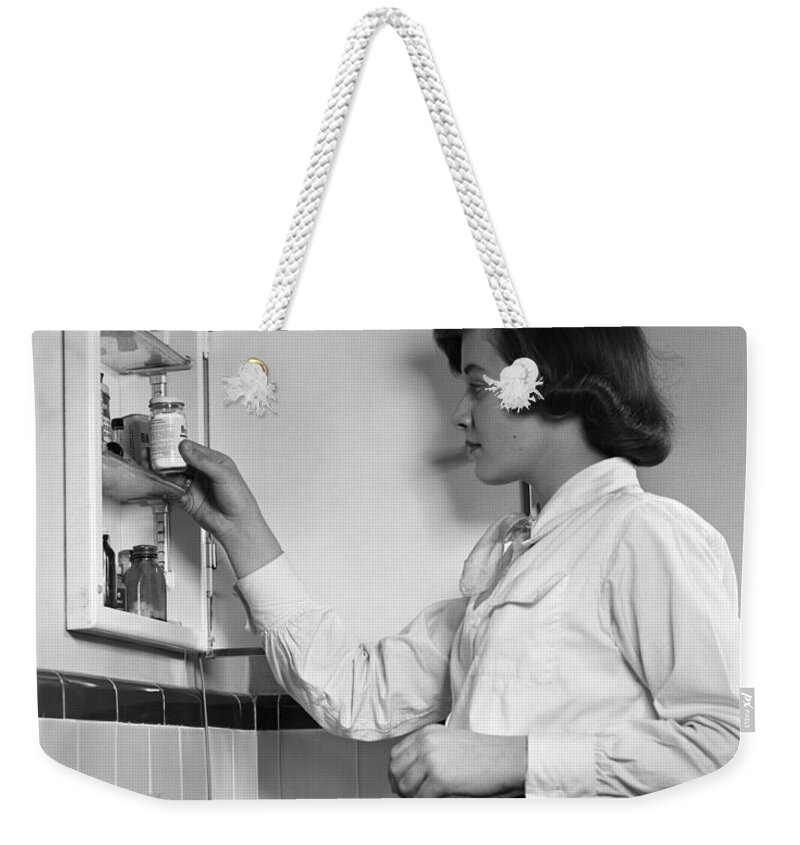 1950s Weekender Tote Bag featuring the photograph Teen Girl At Medicine Cabinet, C.1950s by H. Armstrong Roberts/ClassicStock