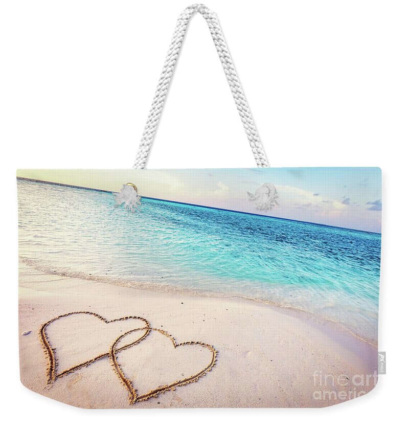 Beach Weekender Tote Bag featuring the photograph Two hearts drawn on sand of a tropical beach at sunset. by Michal Bednarek