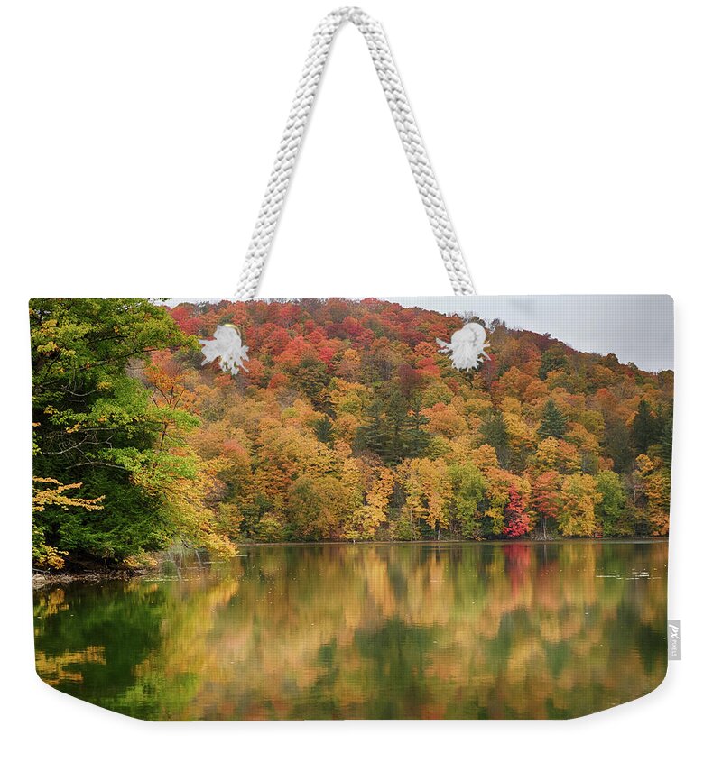 Abenaki Weekender Tote Bag featuring the photograph Vermont fall foliage reflected on Pogue Pond by Jeff Folger