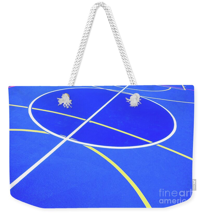 Abstract Weekender Tote Bag featuring the photograph Design of a sports field, with blue background and red and yellow white lines creating strange straight lines and curves, to use with copy space. #1 by Joaquin Corbalan
