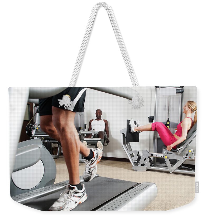 Three Quarter Length Weekender Tote Bag featuring the photograph People Exercising In Health Club #1 by Erik Isakson