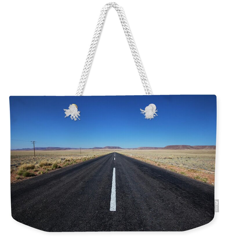 Namibia Weekender Tote Bag featuring the photograph A Paved Road In A Rural Area With Blue by Lars Froelich / Design Pics