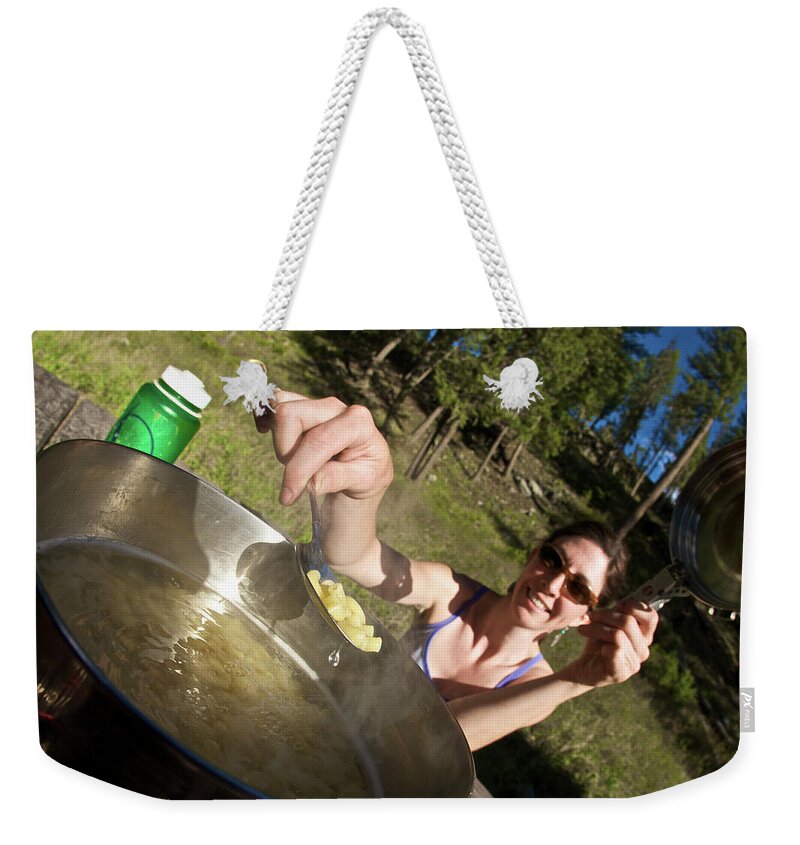 Camping Weekender Tote Bag featuring the photograph A Young Woman Cooks Her Macaroni Dinner by Derek Diluzio