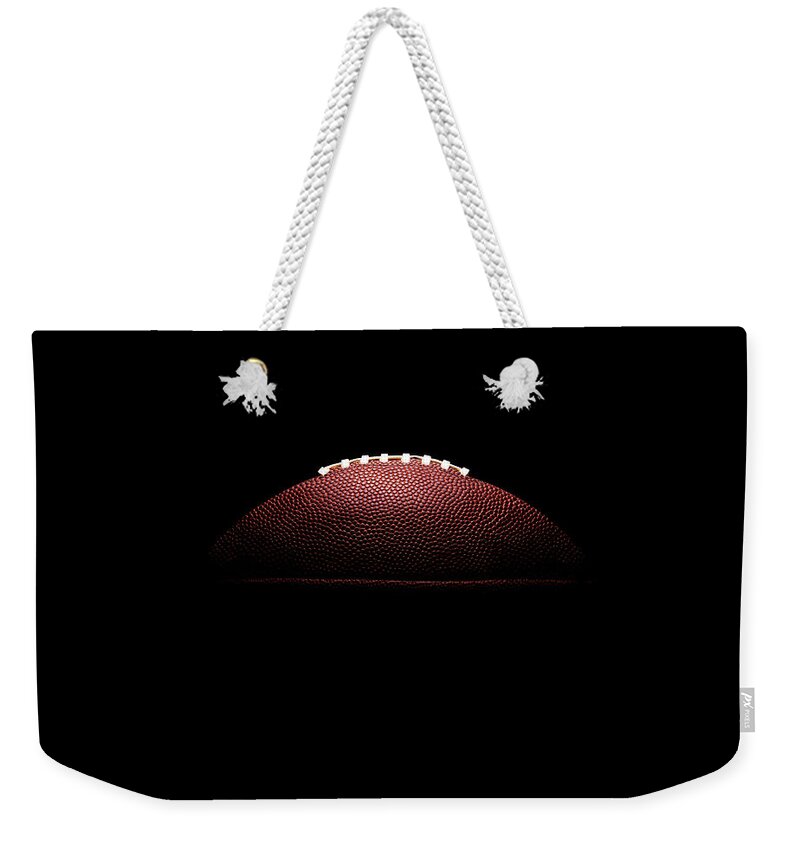 American Football Weekender Tote Bag featuring the photograph American Football Ball On Black by Thomas Northcut
