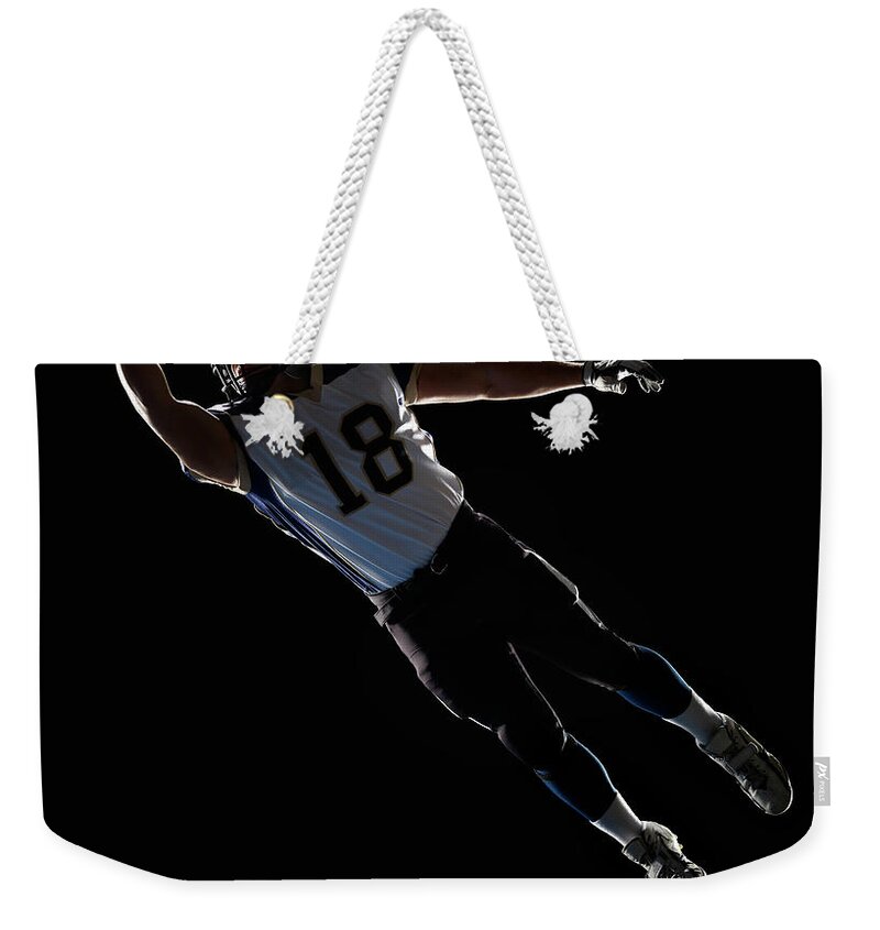 Sports Helmet Weekender Tote Bag featuring the photograph American Football Player Leaping To by Lewis Mulatero