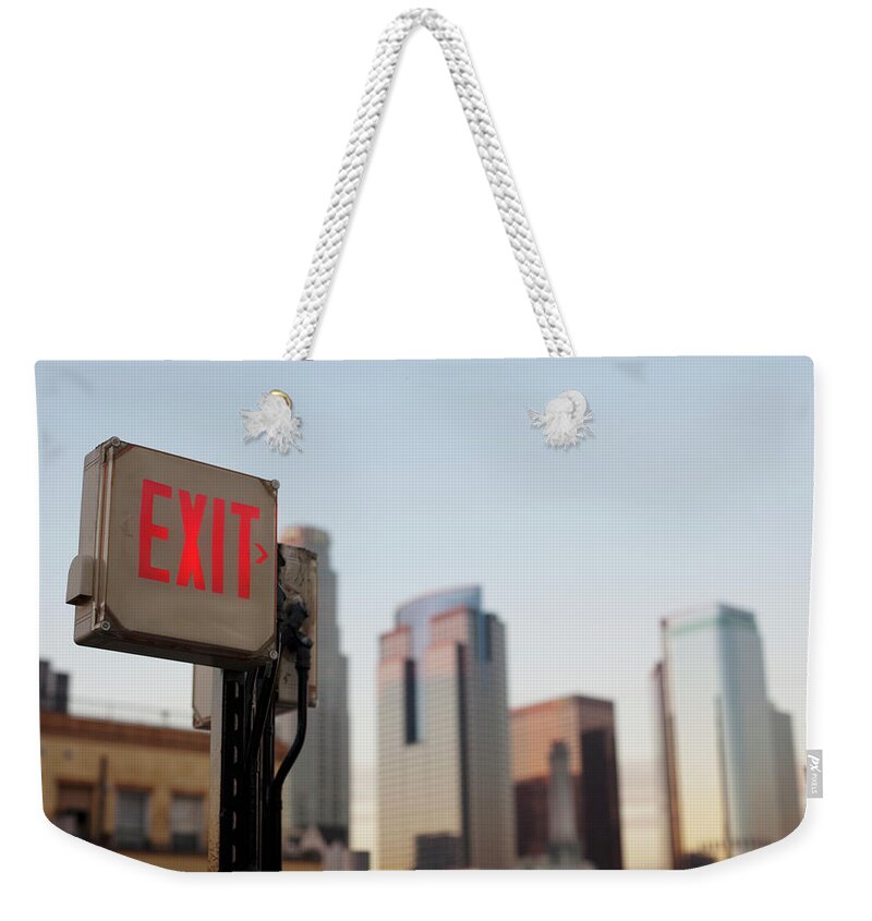 Downtown District Weekender Tote Bag featuring the photograph An Exit Sign In Fron Of A Big City by Frank Rothe