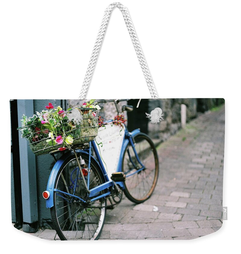 Tranquility Weekender Tote Bag featuring the photograph Basket Of Flowers On Old Blue Bicycle by Ailbhe O'donnell