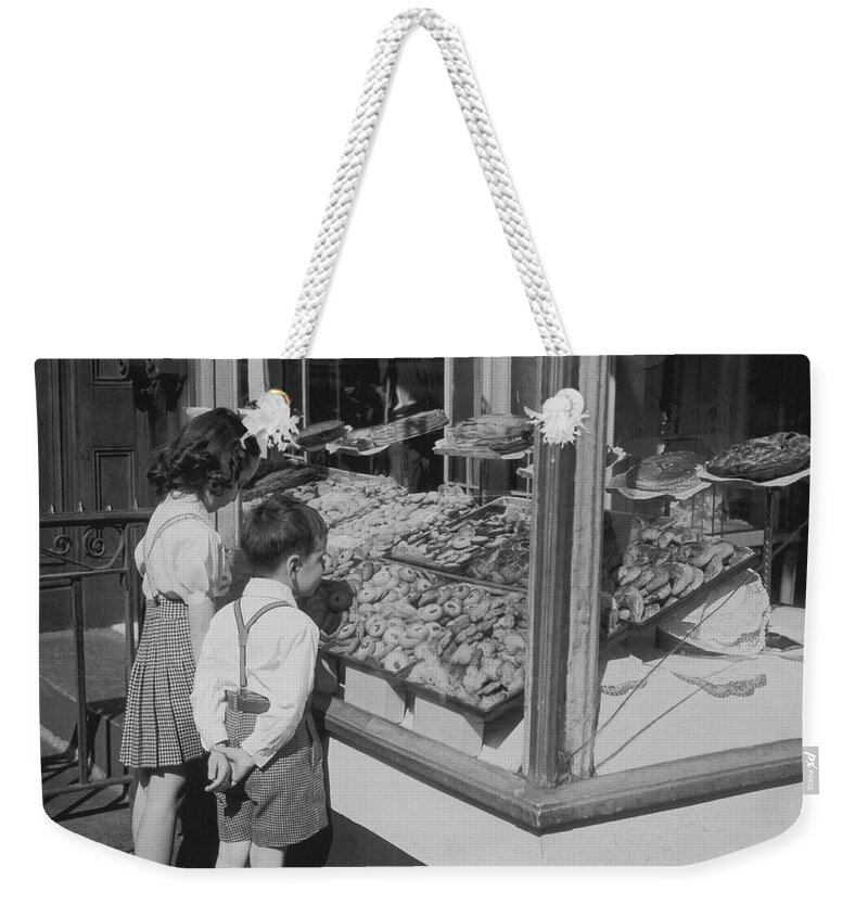 Child Weekender Tote Bag featuring the photograph Boy And Girl Looking In At Bakery by Fpg