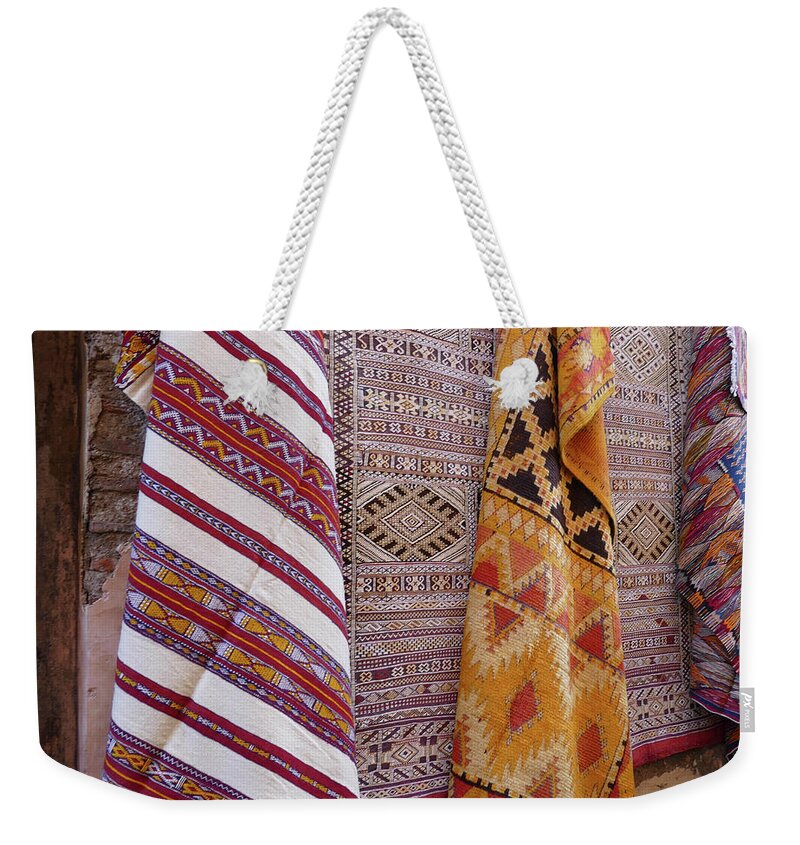 Bright Colored Weekender Tote Bag featuring the photograph Bright colored patterns on throw rugs in the medina bazaar by Steve Estvanik