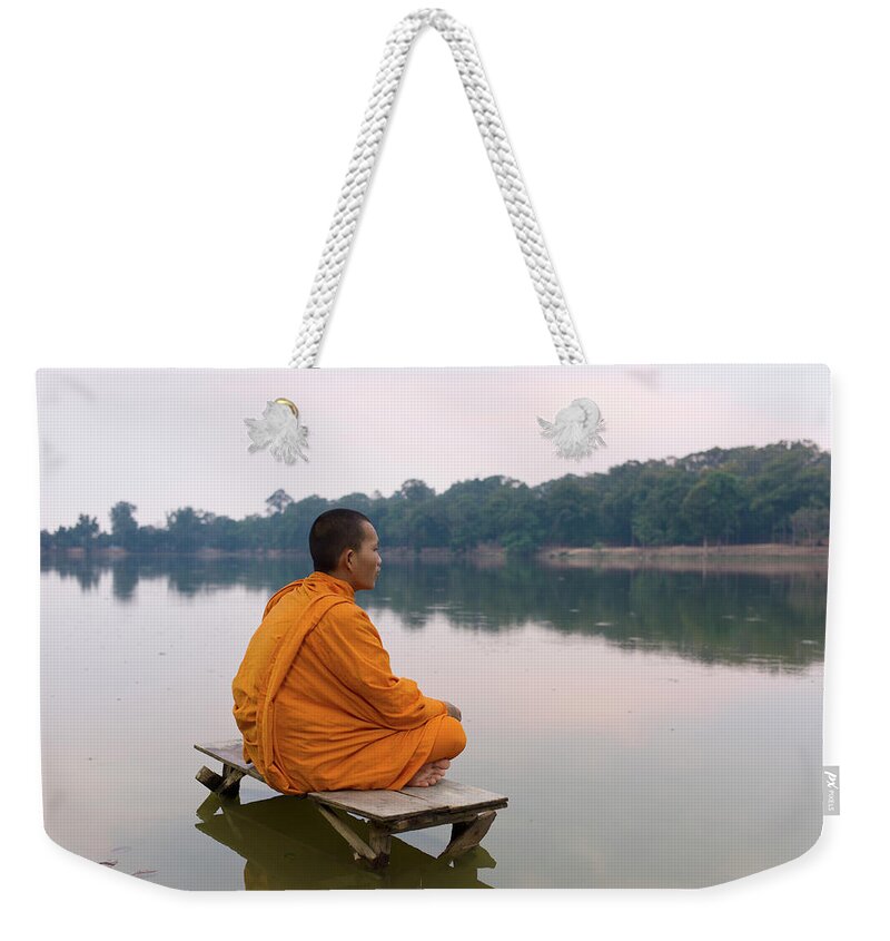 Three Quarter Length Weekender Tote Bag featuring the photograph Buddhist Monk Sitting On Waters Edge by Martin Puddy