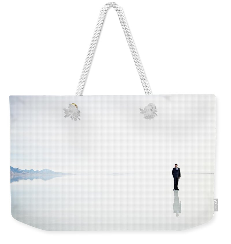 Problems Weekender Tote Bag featuring the photograph Businessman Standing Alone On Surface by Thomas Barwick