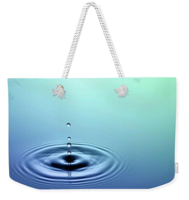 Water Surface Weekender Tote Bag featuring the photograph Close-up Photo Of Water Dripping Into A by Trout55