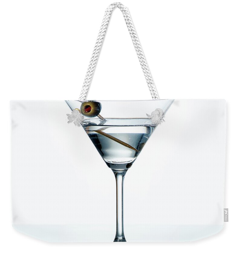 Martini Weekender Tote Bag featuring the photograph Dry martini with green olive in cocktail glass over white backgr by Jelena Jovanovic