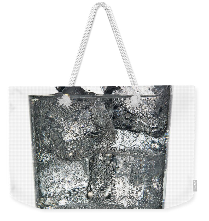 White Background Weekender Tote Bag featuring the photograph Glass Of Ice Cubes In Fizzy Drink by Walter Zerla