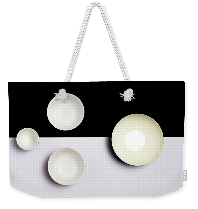 Still-life Weekender Tote Bag featuring the photograph Group of empty ceramic bowls of on a black and white surface by Michalakis Ppalis