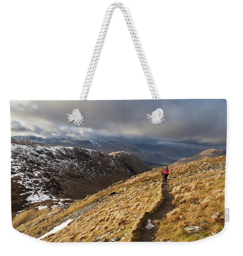 Grass Weekender Tote Bag featuring the photograph Hiker Follows Path Along Mountainside by Ascent Xmedia