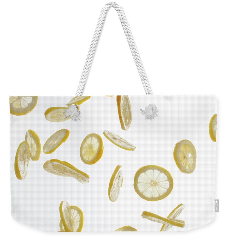White Background Weekender Tote Bag featuring the photograph Lemon Slices Against A White Background by Dual Dual