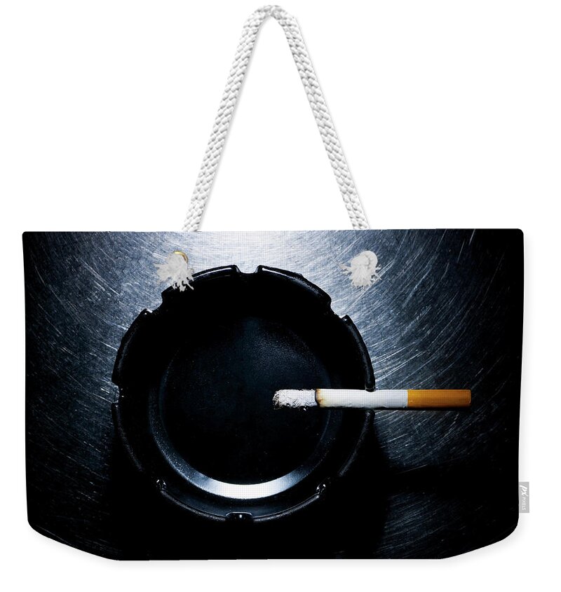 Part Of A Series Weekender Tote Bag featuring the photograph Lit Cigarette And Ashtray On Stainless by Ballyscanlon