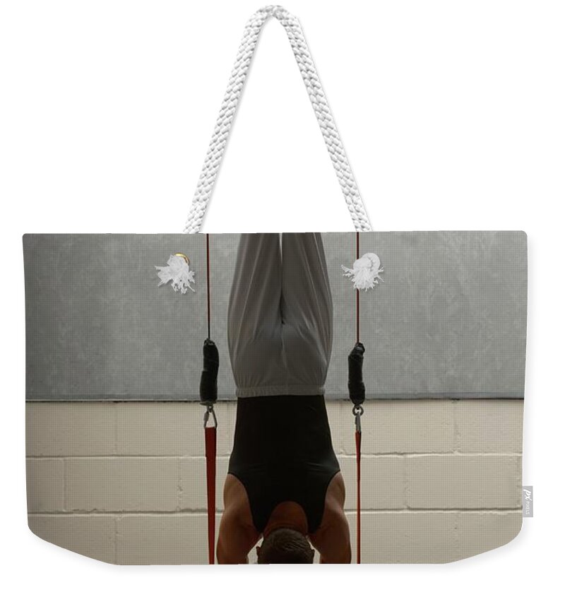 Hanging Weekender Tote Bag featuring the photograph Male Gymnast Balancing Upside Down On by Romilly Lockyer