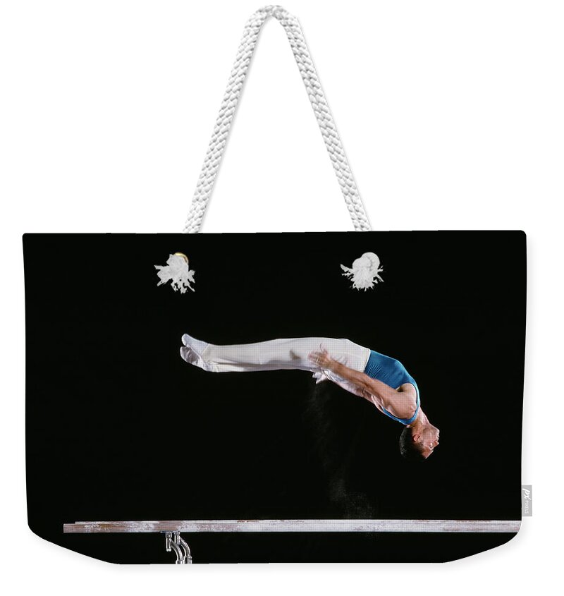 One Man Only Weekender Tote Bag featuring the photograph Male Gymnast Performing On Parallel Bars by David Madison