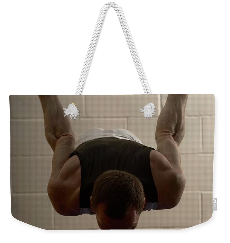 Hanging Weekender Tote Bag featuring the photograph Male Gymnast Performing On Rings by Romilly Lockyer