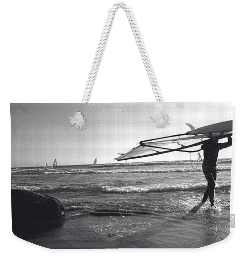 Photography Weekender Tote Bag featuring the photograph Man Carrying A Surfboard Over His Head by Panoramic Images