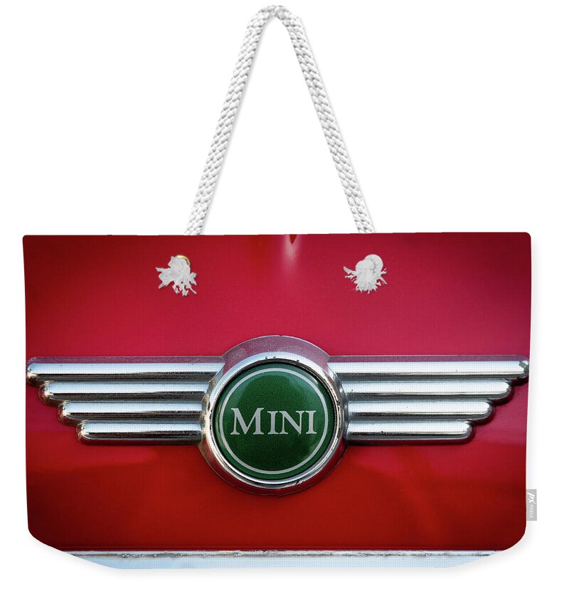Mini Weekender Tote Bag featuring the photograph Mini Cooper car logo on red surface by Michalakis Ppalis