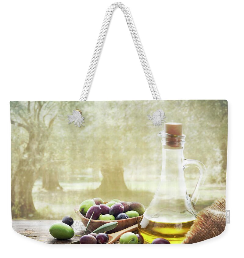 Olive Weekender Tote Bag featuring the photograph Olives and bottle of olive oil on wooden table in olive garden by Jelena Jovanovic