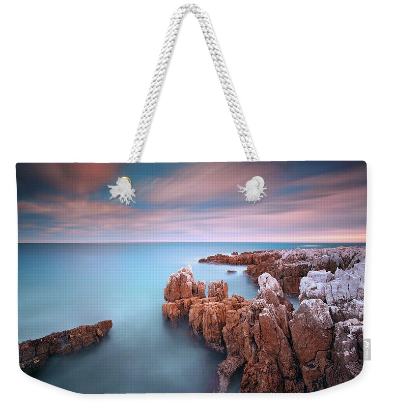 Scenics Weekender Tote Bag featuring the photograph Rocks In Sea At Sunset by Eric Rousset