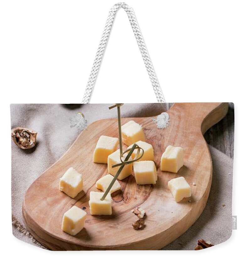 Ip_11342868 Weekender Tote Bag featuring the photograph Small Cubes Of Cheese On An Olive Wood Chopping Board With Walnuts by Natasha Breen