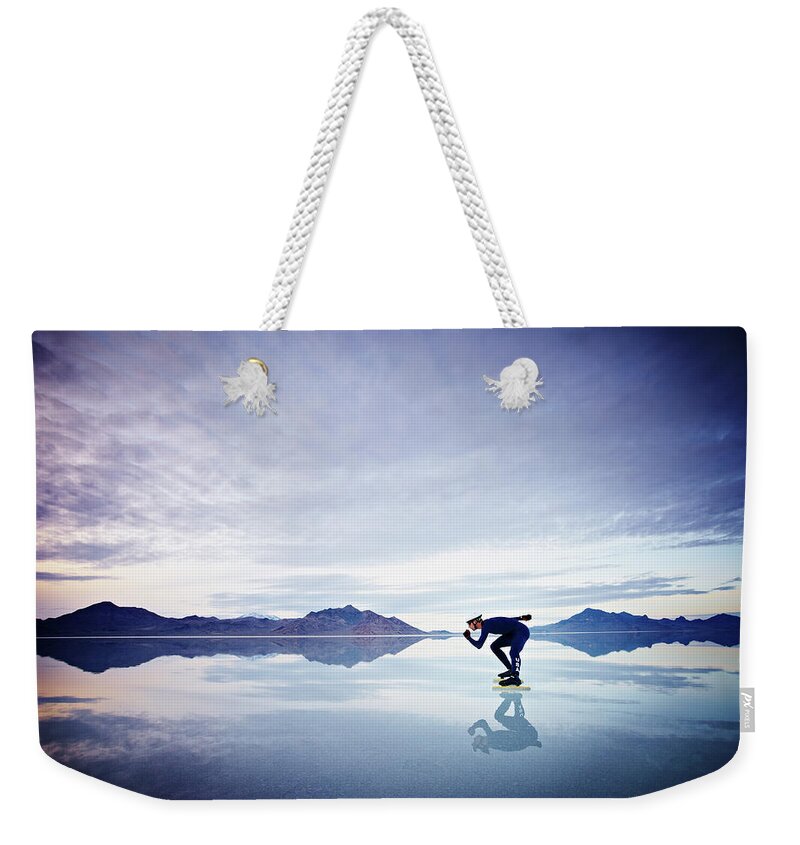 Scenics Weekender Tote Bag featuring the photograph Speed Skater Skating On Calm Lake At by Thomas Barwick