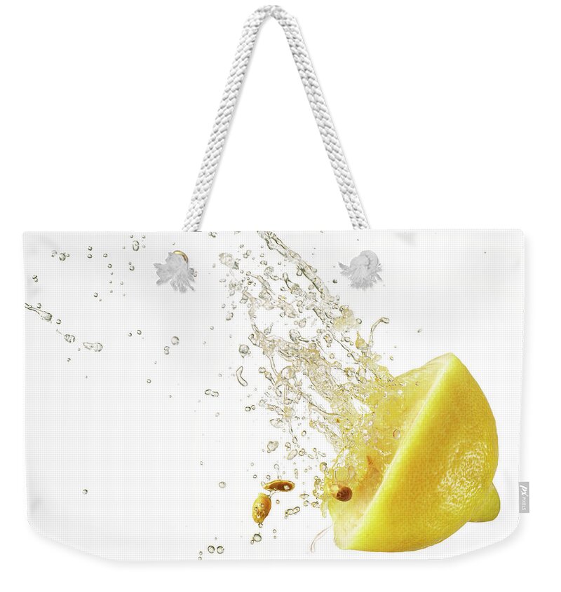 Motion Weekender Tote Bag featuring the photograph Squashed Lemon Slice Spurting Juice And by Yamada Taro