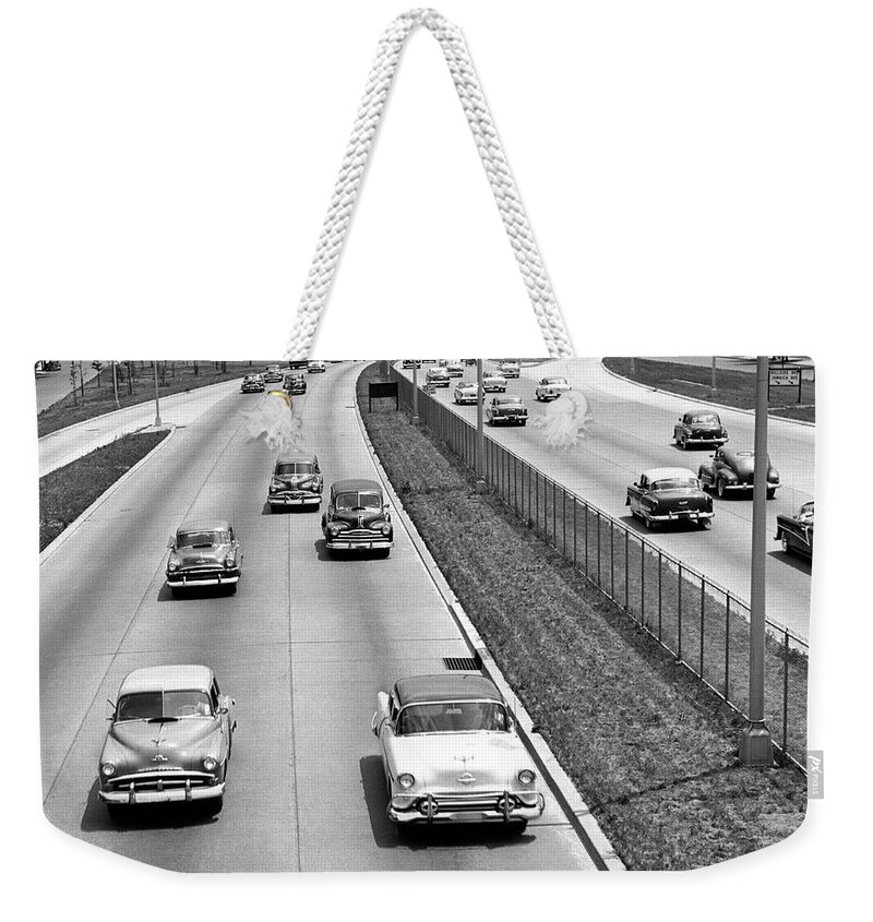 1950-1959 Weekender Tote Bag featuring the photograph Various American Autos On Highway by George Marks