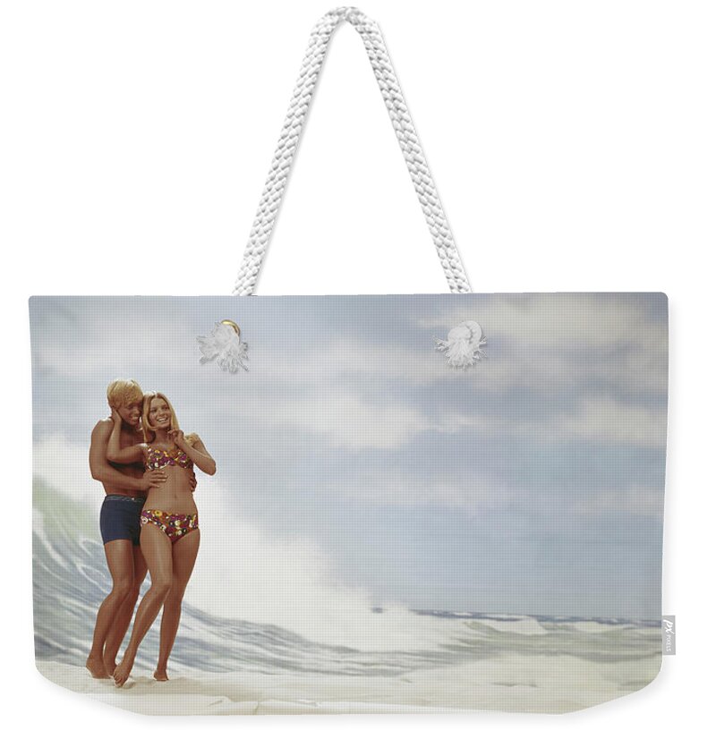 Young Men Weekender Tote Bag featuring the photograph Young Couple Standing On Beach, Smiling by Tom Kelley Archive