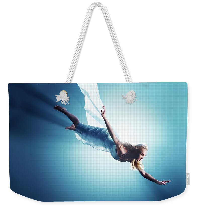 Human Arm Weekender Tote Bag featuring the photograph Young Woman In Air, Low Angle View by Henrik Sorensen
