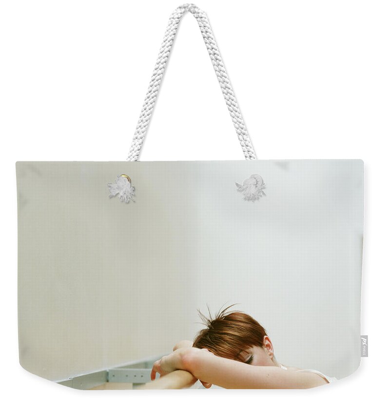Casual Clothing Weekender Tote Bag featuring the photograph Young Woman Leaning Against Rail In by Nick White