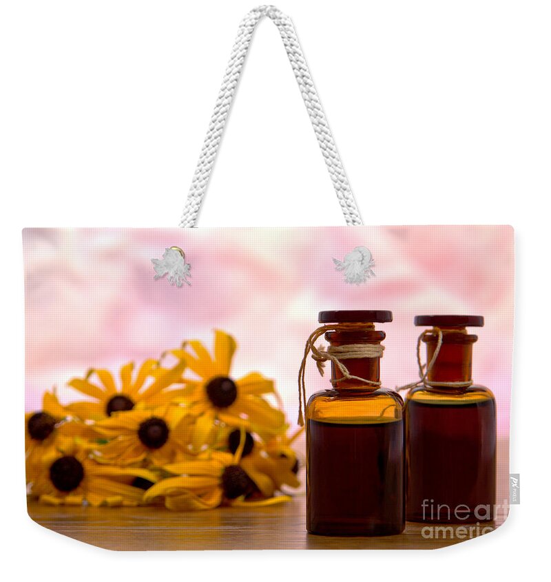 Amber Weekender Tote Bag featuring the photograph Amber Aromatherapy Bottle with Flower Background by Olivier Le Queinec