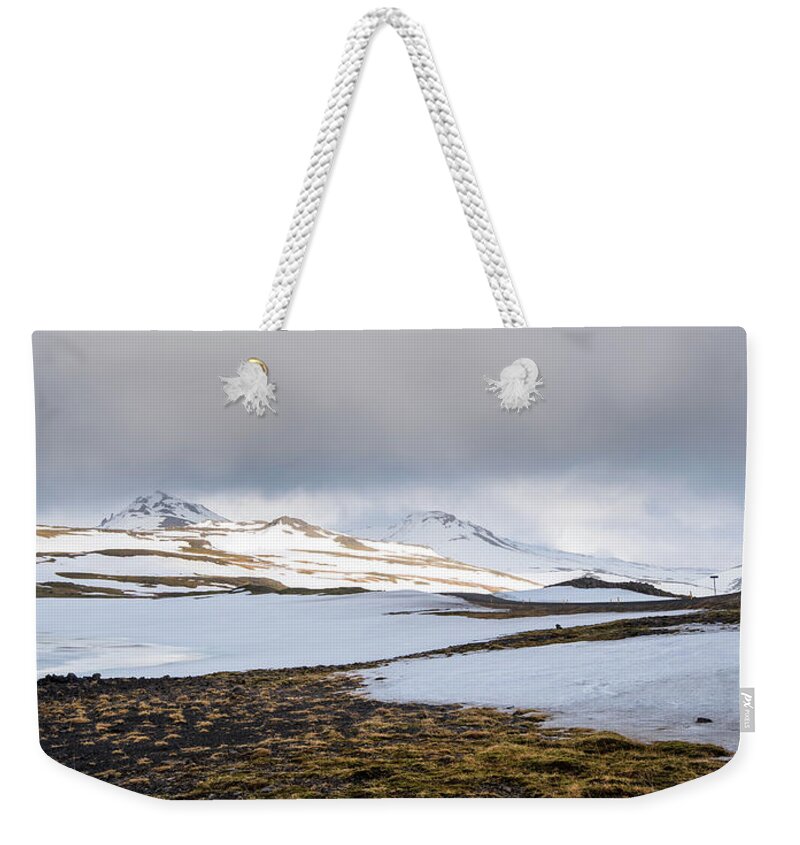 Iceland Weekender Tote Bag featuring the photograph Icelandic landscape with mountains and meadow land covered in snow. Iceland #1 by Michalakis Ppalis