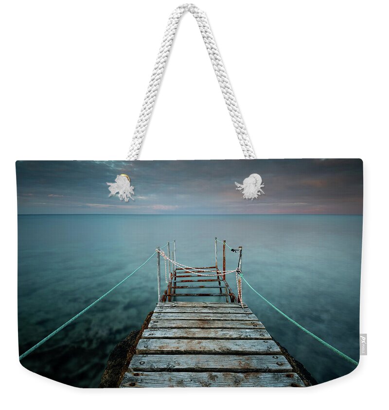 Tranquillity Weekender Tote Bag featuring the photograph Long wooden pier in the sea at sunset. #3 by Michalakis Ppalis